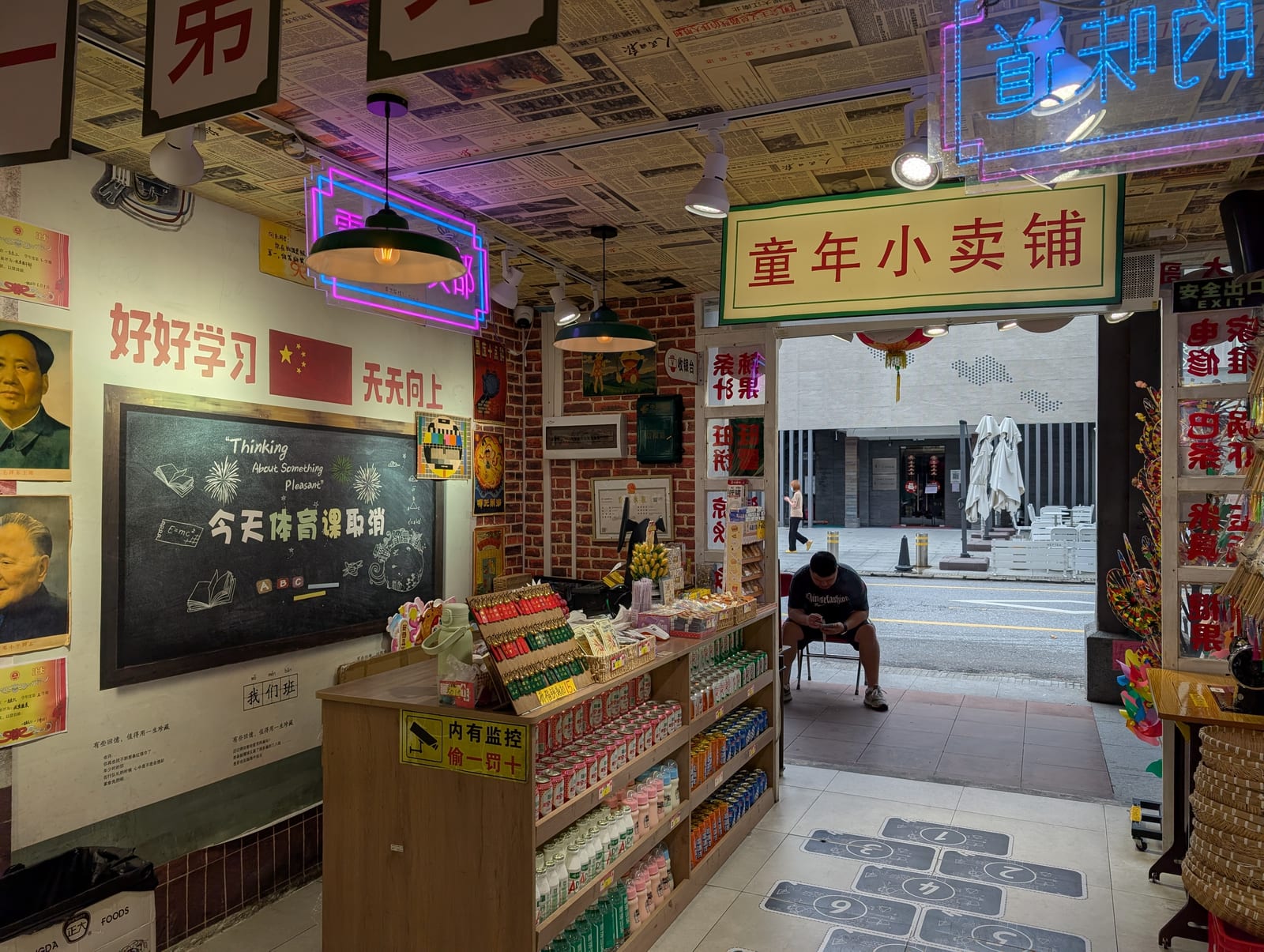 Interior of a nostalgia-themed corner shop with period posters, a chalkboard, neon signs, and shelves of retro snacks