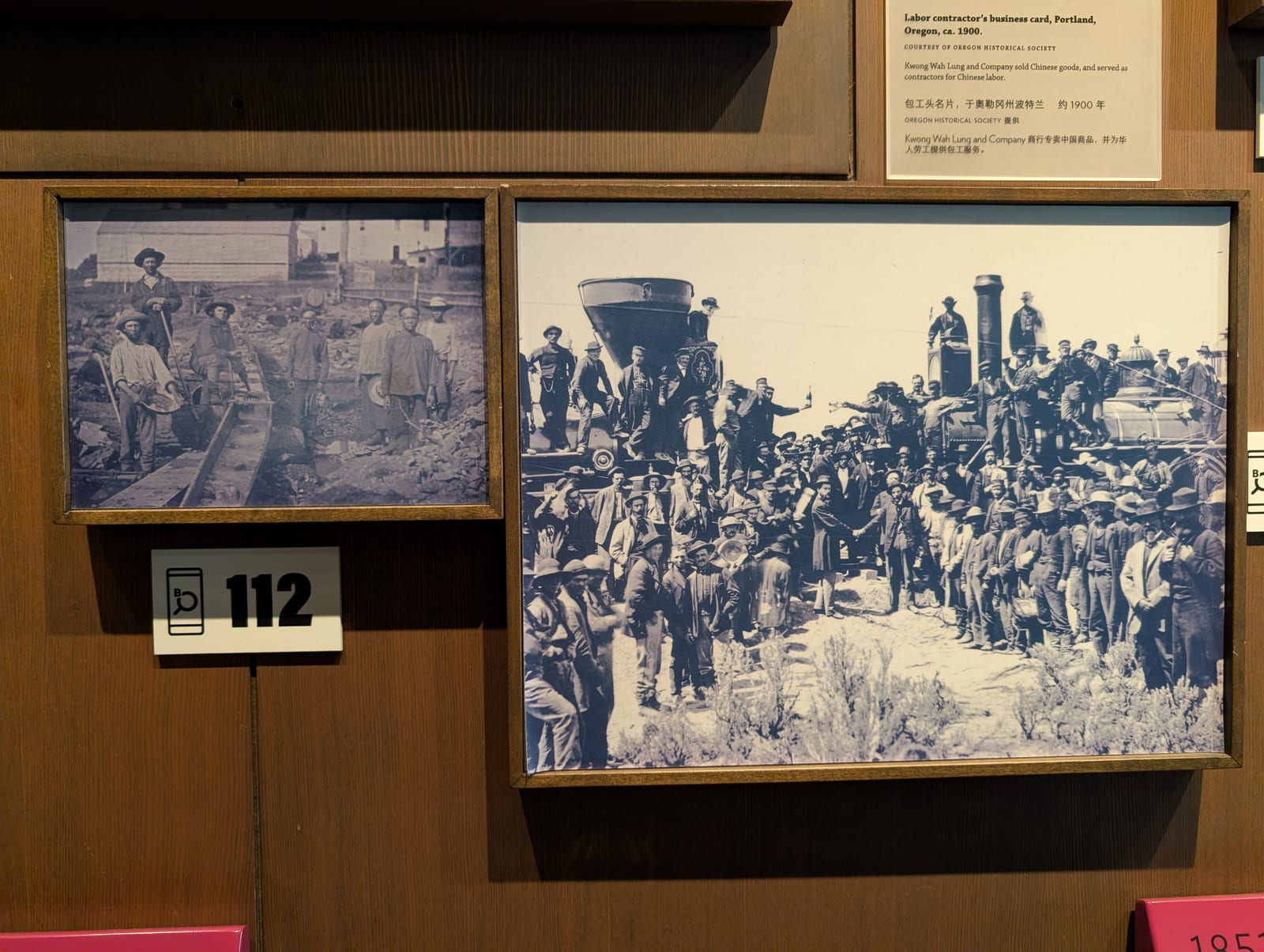 A museum exhibit showing the photograph taken at the completion of the transcontinental railroad beside a smaller image of Chinese laborers at work on the tracks