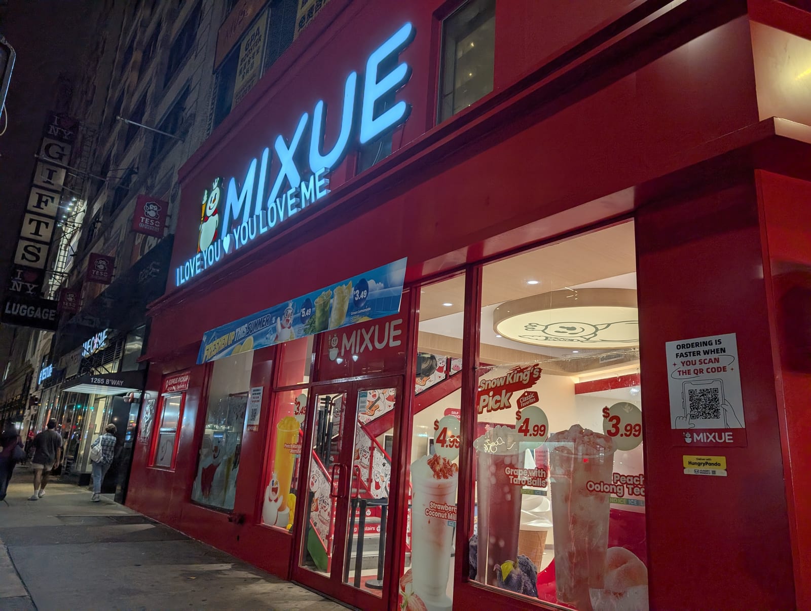 A bright red MIXUE storefront in New York at night, with the Snow King mascot and the slogan I Love You, You Love Me